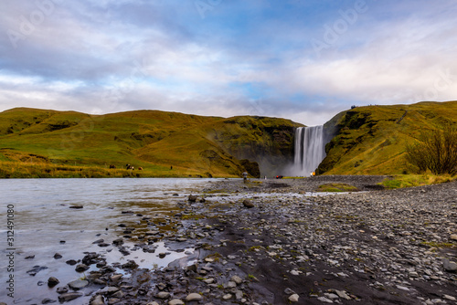 Skogafoss waterfall seen from afar with unrecognisable visitors, Iceland