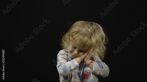 Little baby girl in pajama going to sleep. Black background