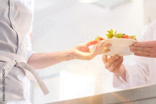 Wallpaper Mural Midsection of chef giving salad plate to waiter in kitchen at restaurant Torontodigital.ca