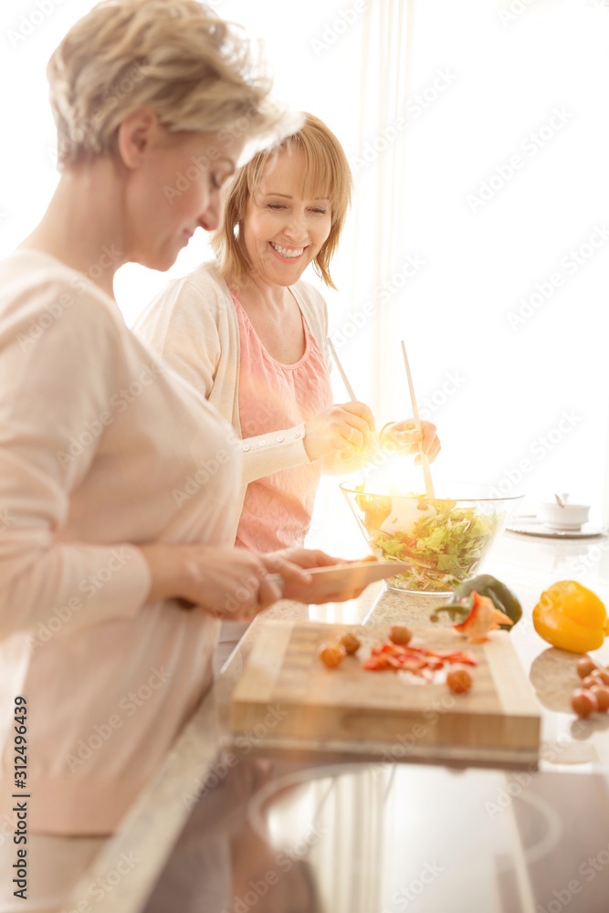 Smiling mature friends preparing meal in kitchen Smiling mature friends preparing meal in kitchen