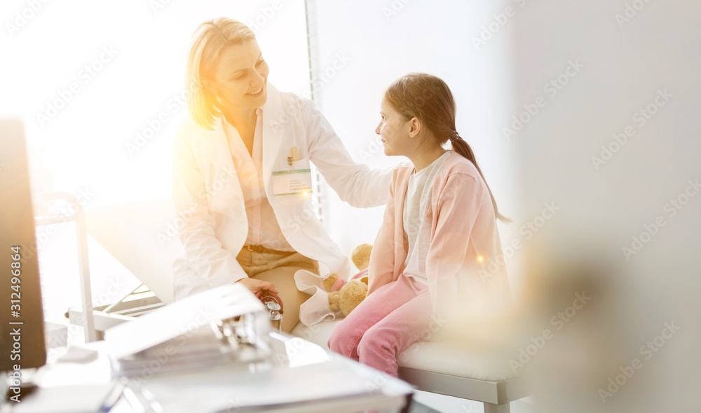 Naklejka premium Smiling doctor talking to girl patient at hospital