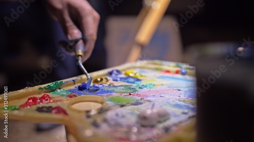 Artist copyist paint seascape with ship in ocean. Craftsman decorator draw as boat sail on blue sea with acrylic oil color. Draw finger  brush  knife palette. Indoor. Close up cinematic look.