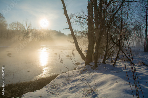 A crispy winter morning with a beautiful sunrise by the river where the fog rises