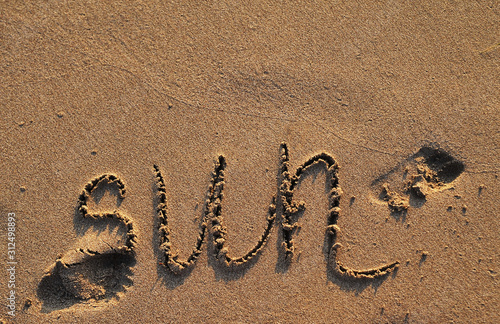 Symbol sun drawn on sand. Summertime concept.