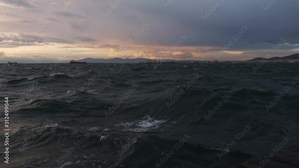 Beautiful waves during a purple sunset and mountains in the background - Wide shot Beautiful waves during a purple sunset and mountains in the background - Wide shot