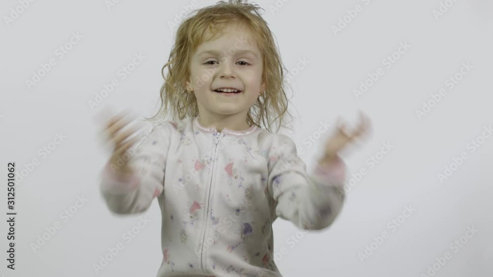 Little baby girl in pajama is fooling around and make faces. White background Little baby girl in pajama is fooling around and make faces. White background