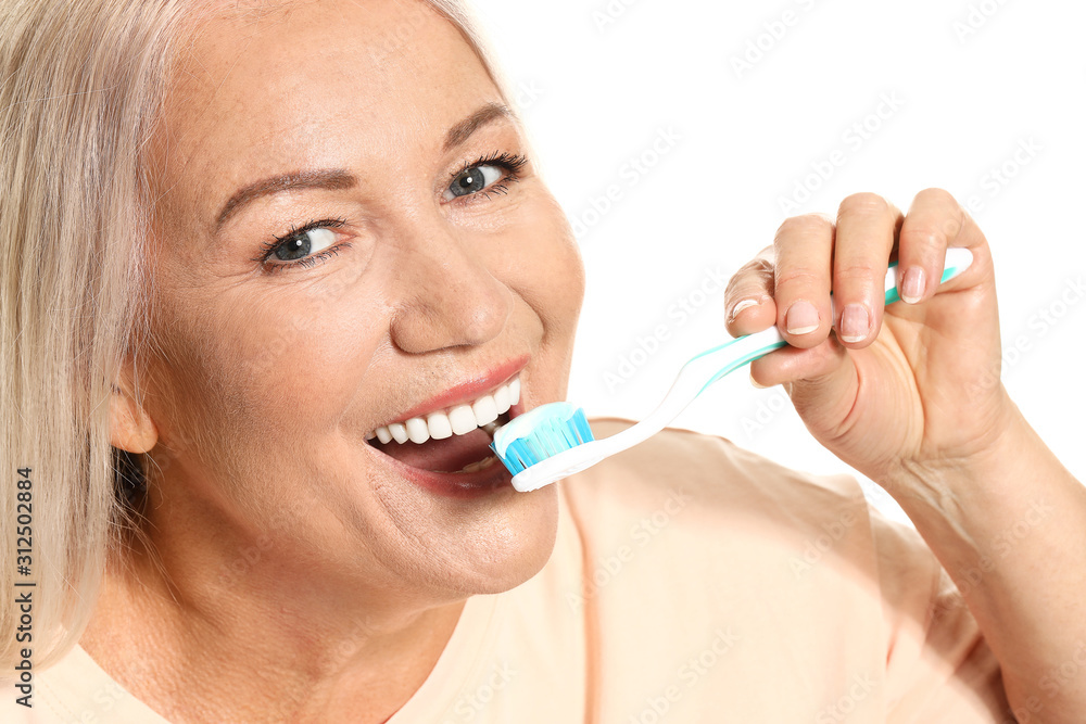 Mature woman brushing teeth on white background