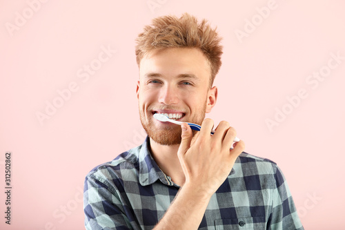 Young man brushing teeth on...