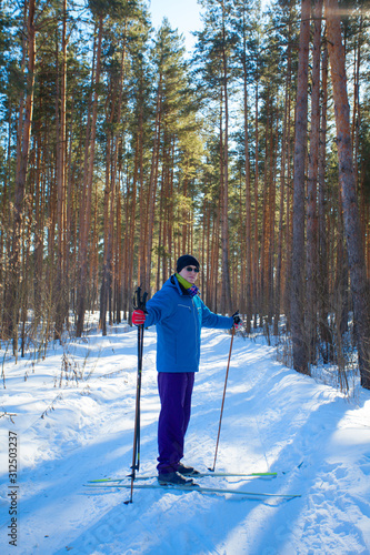 handsome man with skis in winter forest