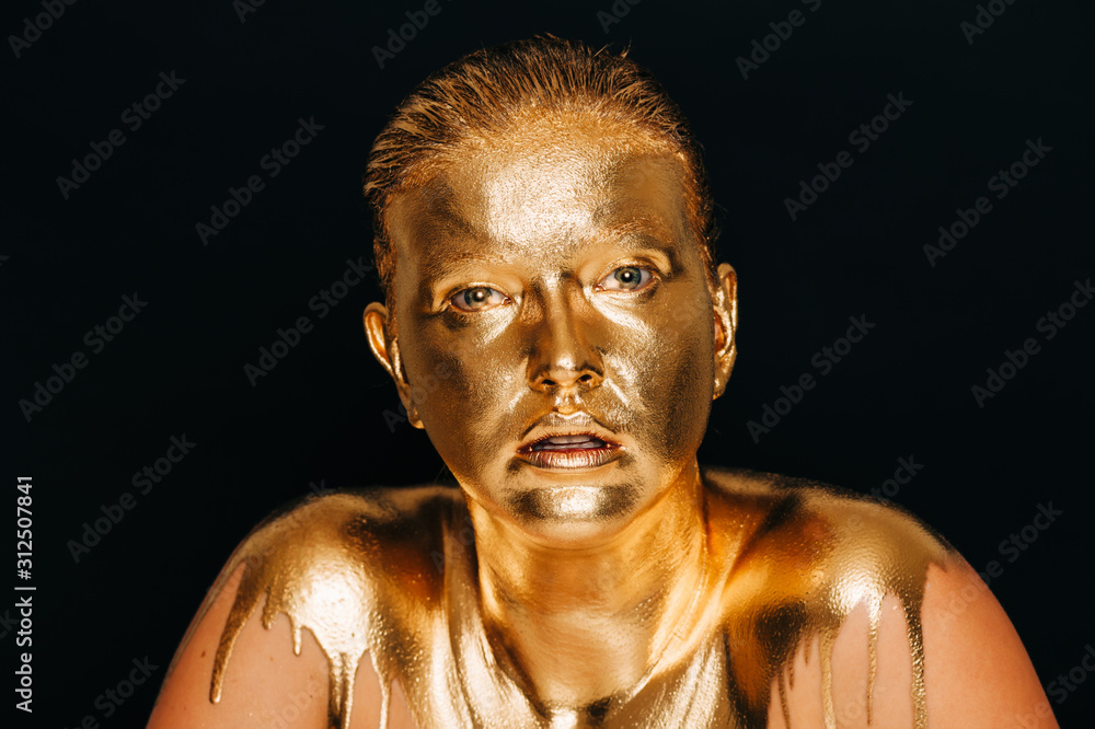 Close up image of young beautiful woman covered with golden paint