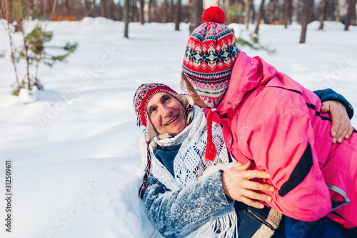 Valentine's Day. Senior couple hugging in winter forest. Man and woman lying in snow and having fun