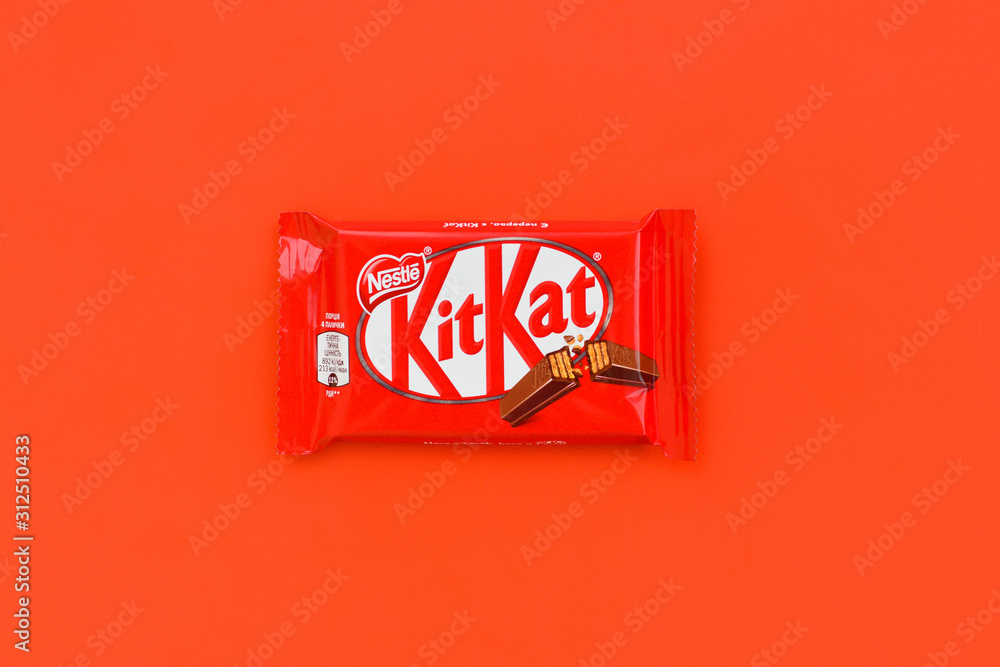 Kit Kat chocolate bar in red wrapping lies on red background. Kit kat