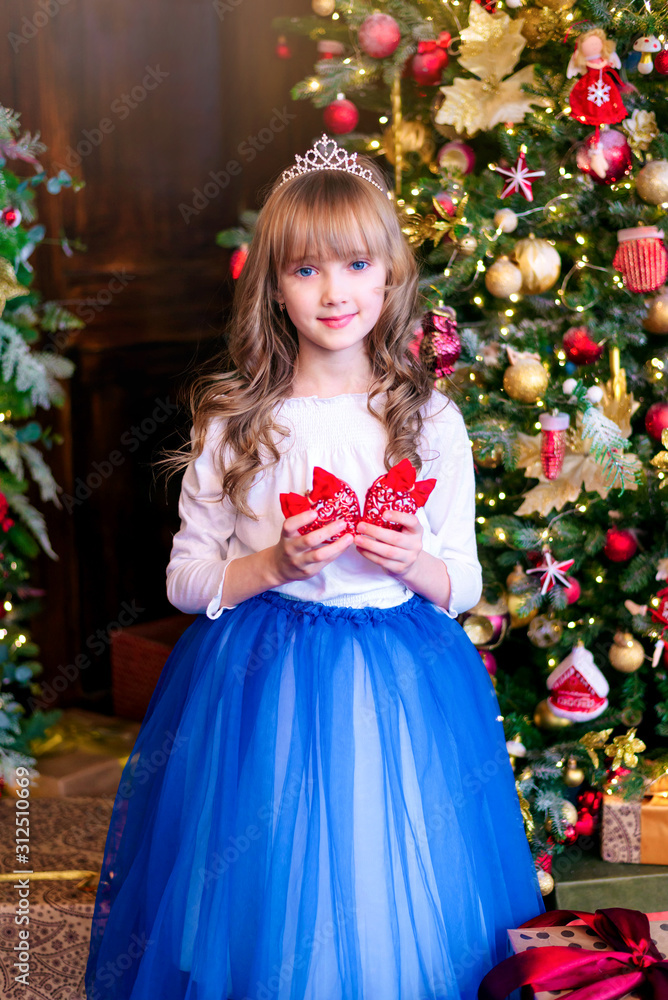 Beautiful blonde girl stands at the Christmas tree with gifts. Holidays, sale concept. Beautiful blonde girl stands at the Christmas tree with gifts. Holidays, sale concept.
