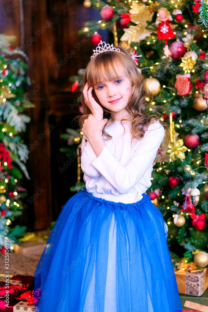 Beautiful blonde girl stands at the Christmas tree with gifts. Holidays, sale concept. Beautiful blonde girl stands at the Christmas tree with gifts. Holidays, sale concept.
