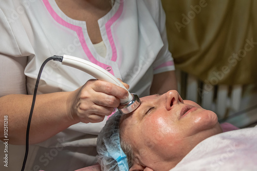 A cosmetic procedure with ultrasonic treatment of the skin of the face is performed for an aged woman. Instrumental effect on the surface of the skin. Improving skin turgor, rejuvenation and healing.