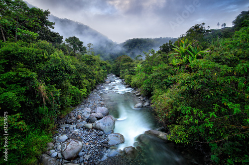 River with big stones and trees, tropic mountain forest during rain, Colombia landscape. Tropic forest in South America.