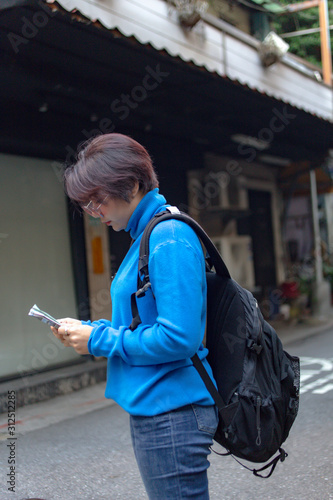 Solo traveller vacations in Asia. Woman tourist using map for searching direction, exploring locations in streets of city while enjoying solo trip in Taipei Taiwan. copy space.