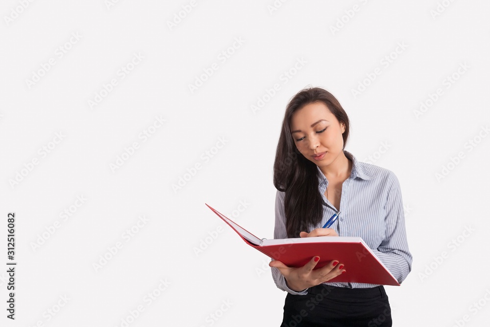 Businesswoman writing in book against gray background Businesswoman writing in book against gray background