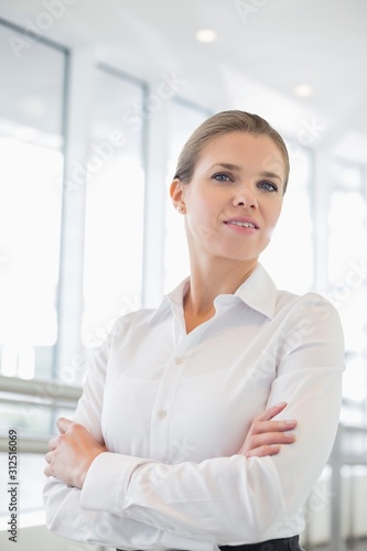 Portrait of confident businesswoman standing arms crossed in office Free Download Portrait of confident businesswoman standing arms crossed in office - GFXLoad