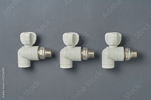 Rows of three polypropylene water faucet for heating radiator lies on dark concrete desk in workshop. Close-up. Top view