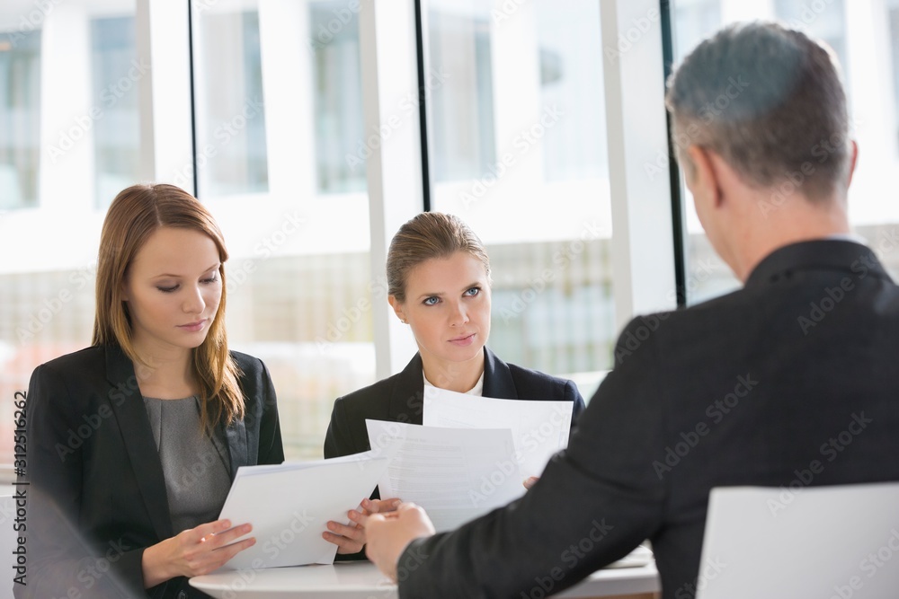 Business people discussing paperwork in office cafeteria Business people discussing paperwork in office cafeteria