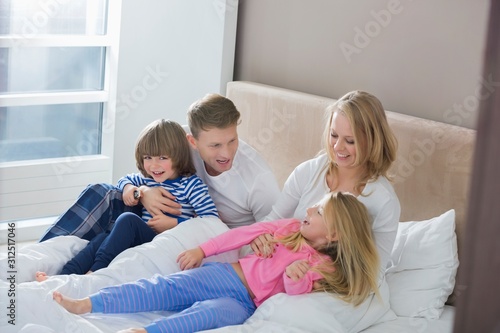 Parents playing with children in bedroom