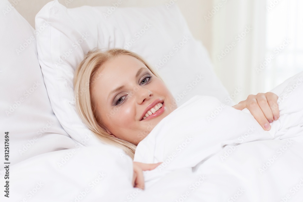 Portrait of beautiful young woman smiling while lying in bed Portrait of beautiful young woman smiling while lying in bed