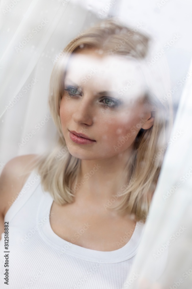 Beautiful young woman looking through hotel window Beautiful young woman looking through hotel window