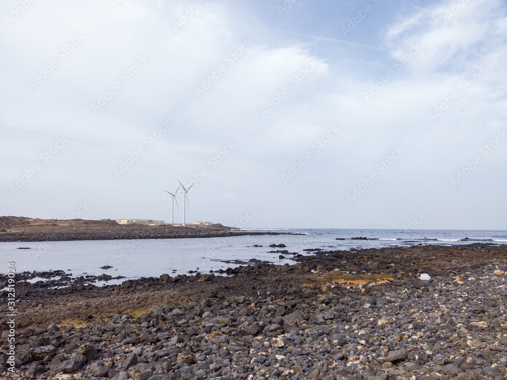 Wind turbines near the sea coast cosastline energy alternative bay beach water sky cloud cloudy white stone rock rocks power