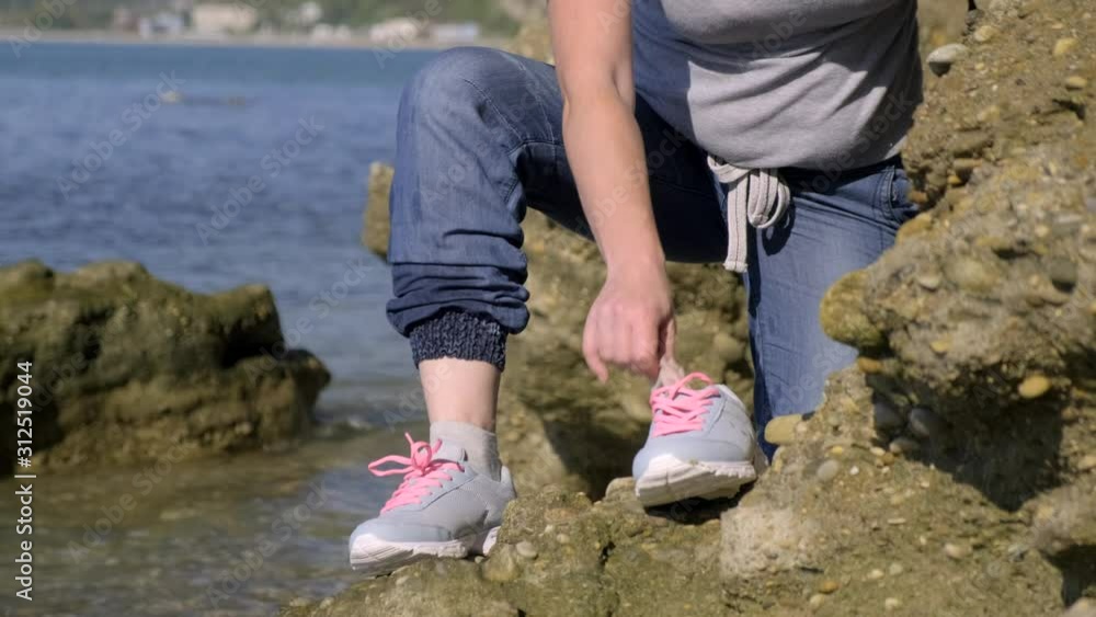 Girl traveler dresses shoes standing on stone shore near sea. Girl traveler dresses shoes standing on stone shore near sea.