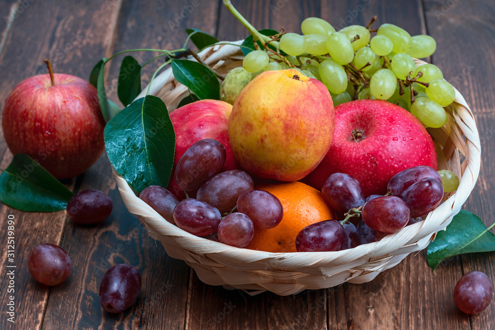 red grape berries and fresh fruits in a straw basket on a dark wooden background. red grape berries and fresh fruits in a straw basket on a dark wooden background.