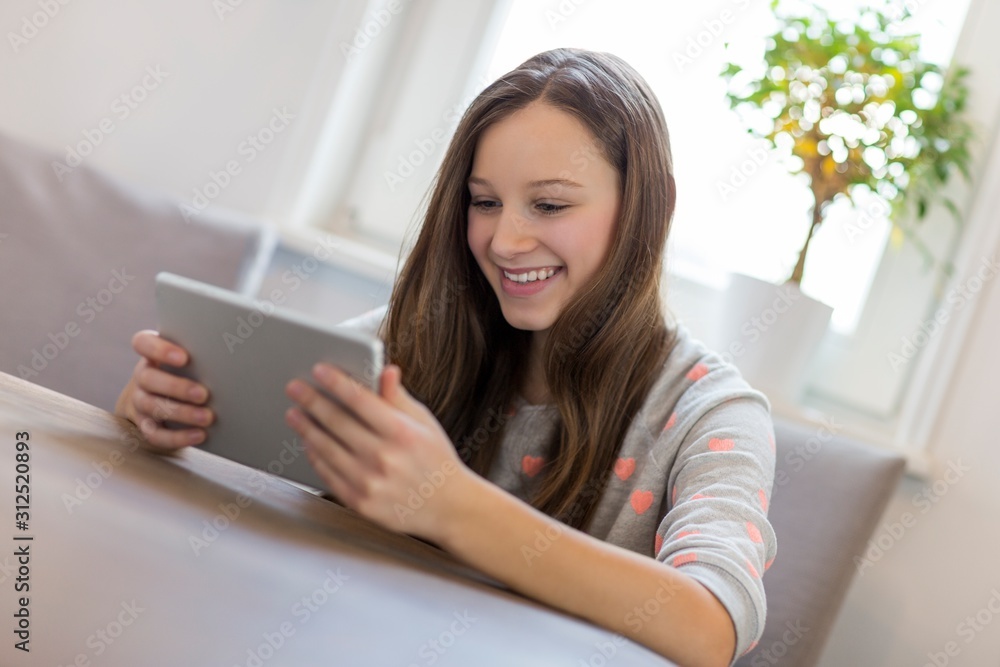 Fototapeta premium Happy girl using digital tablet at home