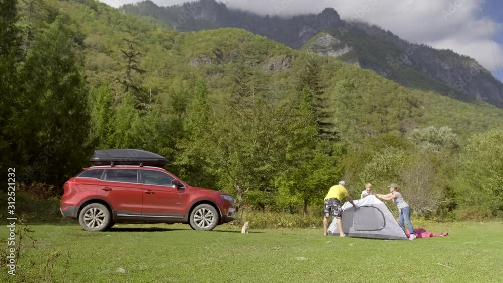 group of friends setting up tourist tent on lawn on background of mountains. group of friends setting up tourist tent on lawn on background of mountains.