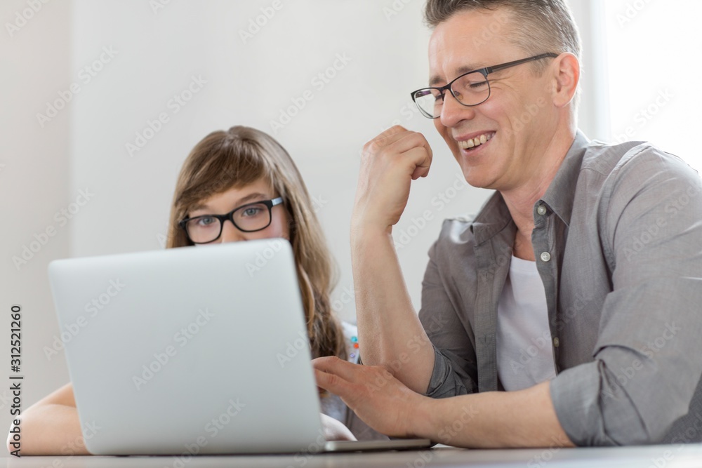 Happy man using laptop with daughter at home Happy man using laptop with daughter at home