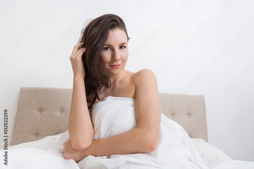 Portrait of sensuous woman covered with bedsheet in bed