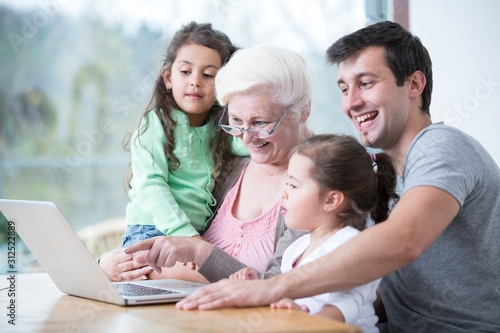 Happy three generation family using laptop at table in house © moodboard
