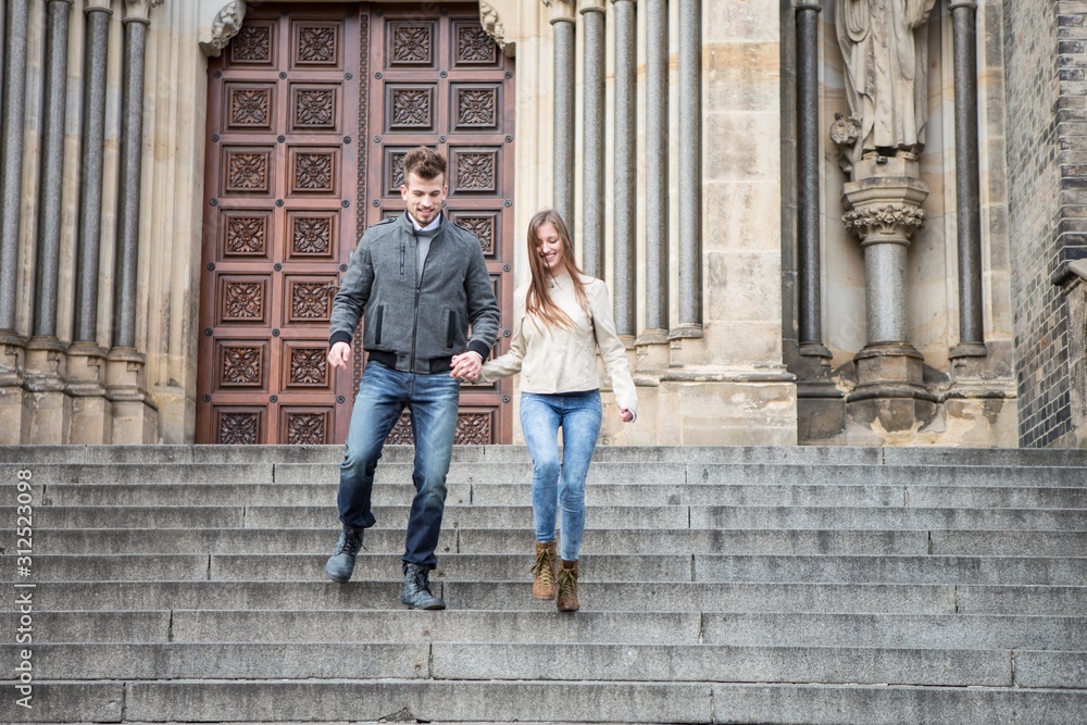 Full length of young couple moving down steps against building