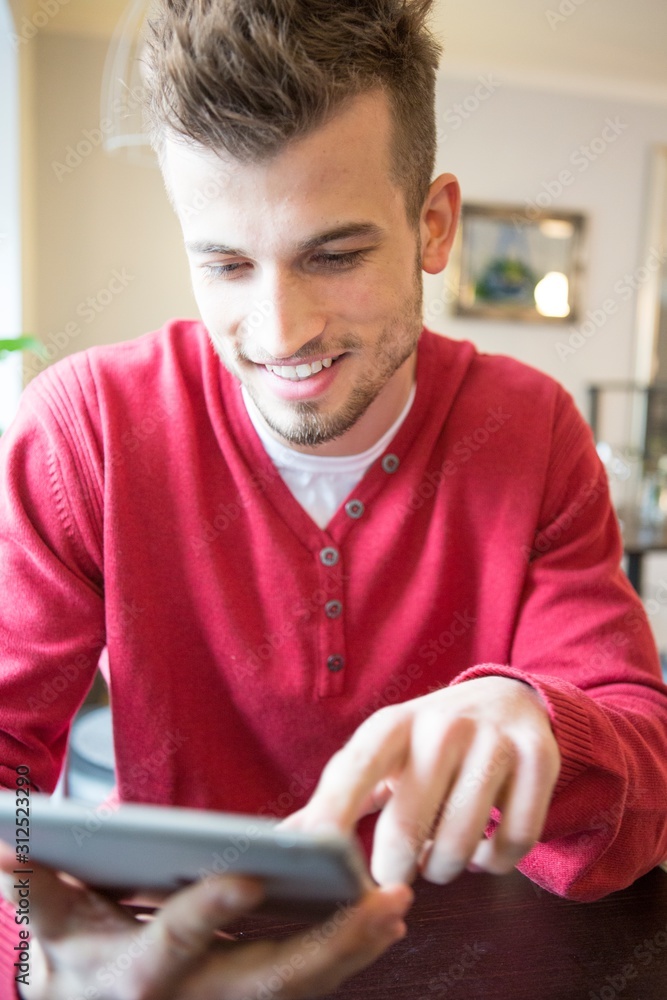 Smiling young man using tablet PC in cafe
