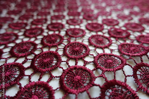 Macro of dark red lacy fabric with circular pattern