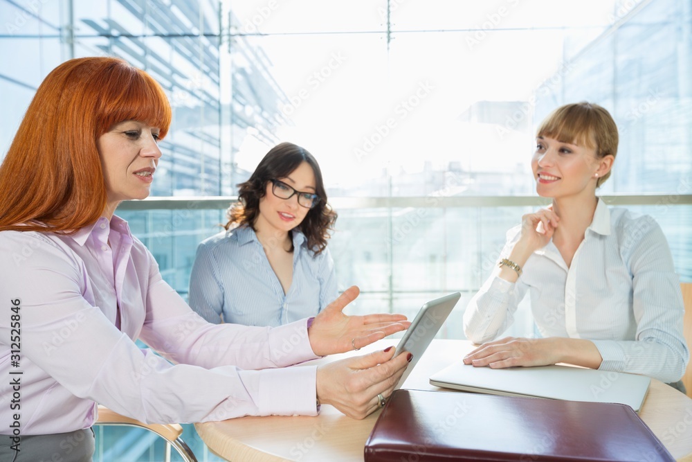 Businesswomen discussing over table PC at table in office Businesswomen discussing over table PC at table in office