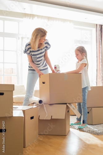 Mother and daughter packing cardboard boxes at home