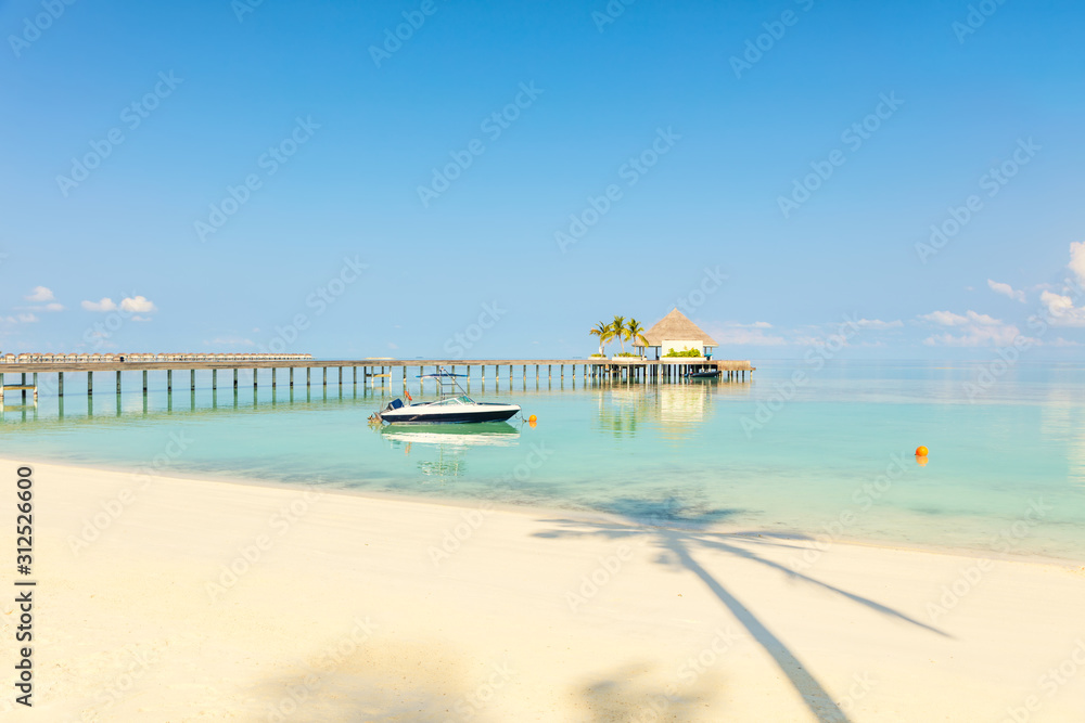 Wooden pier with small sea station place by tropical blue sea, sandy beach and palm tree shade