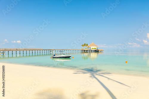 Wooden pier with small sea station place by tropical blue sea, sandy beach and palm tree shade © 18042011