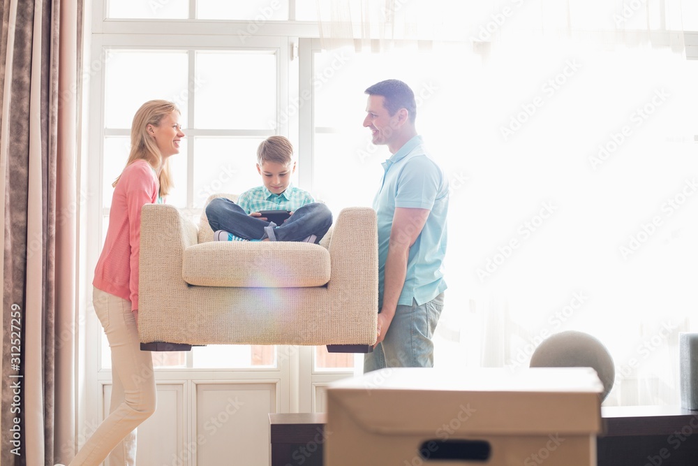 Happy parents carrying son on armchair in new house Happy parents carrying son on armchair in new house