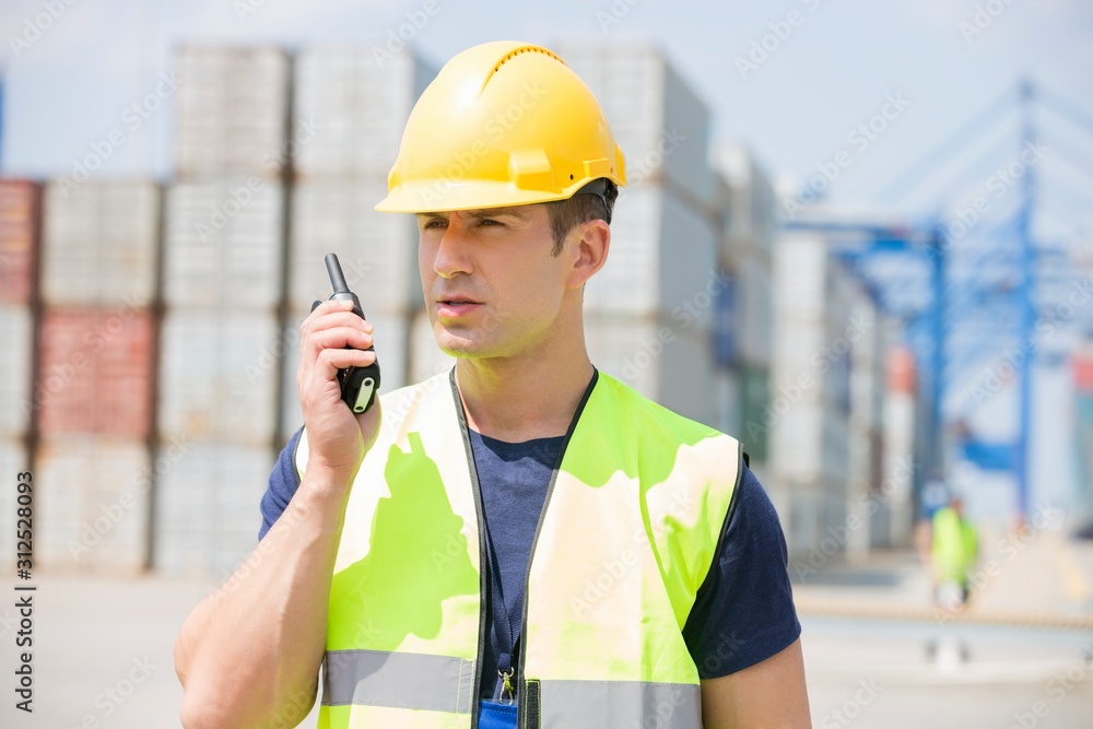Mid adult man using walkie-talkie in shipping yard Mid adult man using walkie-talkie in shipping yard