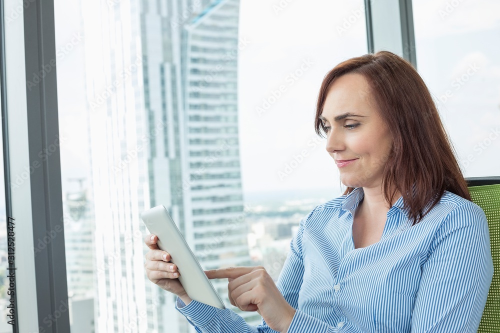Fototapeta premium Mid-adult businesswoman using digital tablet in office
