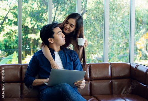 A man is working while his girlfriend serving a coffee