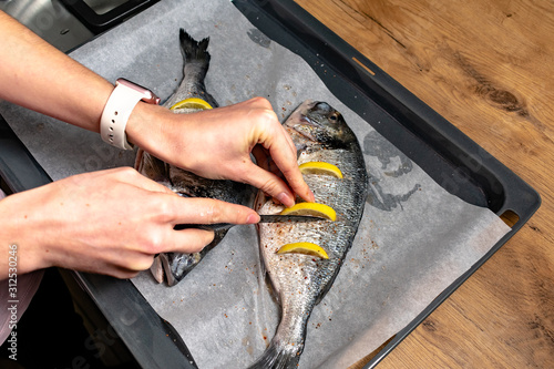 Raw dorado or sea bream fish with lemon slices. Fresh sea fish. Dorado, herbs and spices. Menu photo