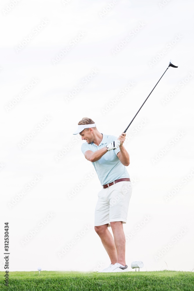 Full-length of mid-adult man swinging golf club against clear sky Full-length of mid-adult man swinging golf club against clear sky