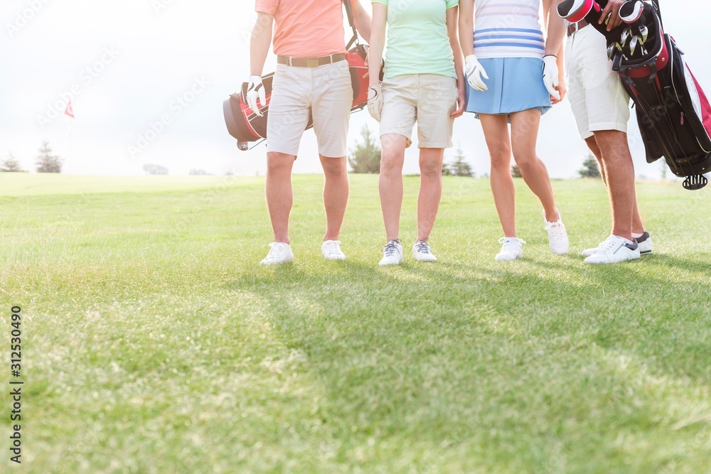 Low section of friends standing at golf course Low section of friends standing at golf course